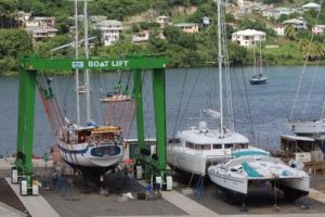 The travel lift at Clarkes Court Boatyard with a yacht on the lift and two catermarans on the dock.