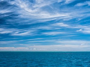 blue water and blue sky with light wispy clouds in the maldives