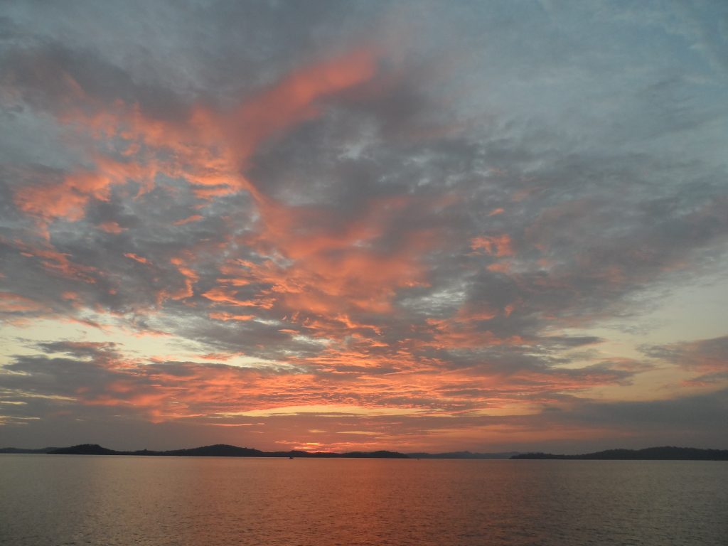 pink and grey sky as the sun sets over a narrow strip of land