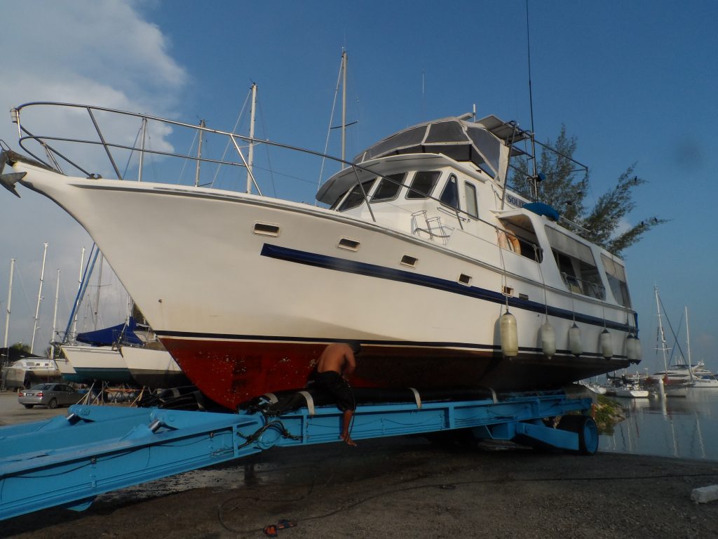 large white motorboat with a red keel supported with poles on a hard standing