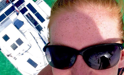 woman on the mast of catamaran looking down to the deck.